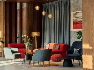 斯克拉斯卡波伦巴Hotel Bergo Resort & SPA的客厅配有红色的沙发和椅子