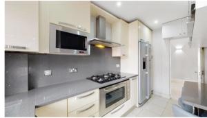 伦敦9 Brentwood Lodge的厨房配有白色橱柜和炉灶烤箱。
