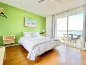 Berthier-sur-MerLa Plage Motel的绿色卧室设有床和大窗户
