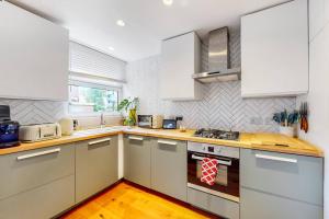 伦敦Charming 2-bedroom maisonette with private garden的厨房配有白色橱柜和炉灶烤箱。