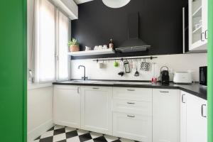 博洛尼亚Green House city center的厨房配有白色橱柜,铺有黑白地板。