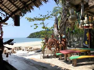 阁帕延岛Rasta Baby Bar & Bungalows - Suitable for young travelers的海滩上带桌子和长椅的海滩