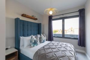 格洛斯特Elliot Oliver - Stunning Three Bedroom Penthouse With Large Terrace & Parking的一间卧室配有一张带蓝色床头板的床和窗户