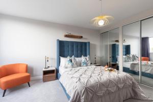 格洛斯特Elliot Oliver - Stunning Three Bedroom Penthouse With Large Terrace & Parking的一间卧室配有一张大床和一张橙色椅子