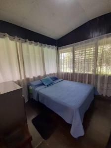Río SerenoHospedaje Finca Agroturistica Doña Rufa的一间卧室配有一张带蓝色床单和窗户的床。