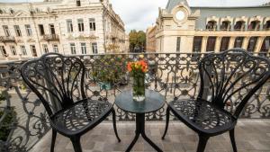第比利斯TownHouse Tbilisi Boutique Hotel的阳台上配有两把椅子和一张桌子,花瓶上放着鲜花