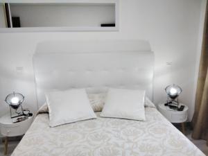 布迪皮拉格斯Albergue Piedad的一间白色卧室,配有两张床和两盏灯。
