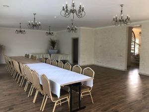 马里扬泊列Marių įlanka的一间大型用餐室,配有白色的桌子和椅子