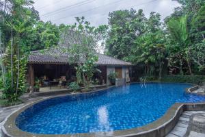 JarakanDream Village的一座树木繁茂的房屋前的游泳池