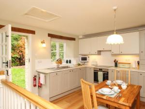 UpweyMill Cottage的厨房配有白色橱柜和木桌