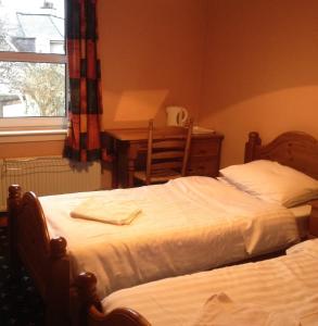 爱丁堡双狮酒店的一间卧室设有两张床、一张桌子和一个窗口。