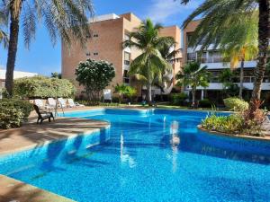 波拉马尔¡Hermoso Apartamento en Loma Real!的棕榈树建筑前的游泳池