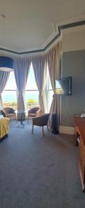 伊斯特布恩亚历山大酒店的客厅设有大窗户和电视。