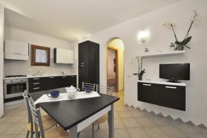 圣特奥多罗Residence Le Zagare的厨房配有桌椅和电视。
