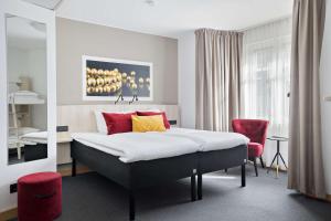 乌普萨拉斯维瓦贝斯特韦斯特酒店的一间卧室配有一张床和一张红色椅子