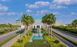 开罗开罗凯宾斯基御美心皇宫酒店的一座在道路前方有棕榈树的建筑