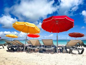 东方湾Princess Anouk Beachfront Orient Bay Deluxe 3 BDR的海滩上的一组椅子和遮阳伞