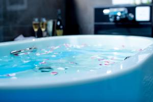 冈山ホテルウォーターゲート岡山的装满蓝色液体的浴缸,有喷水