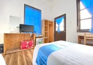 格劳Hinode Hotel ဟိနောဒေ့ဟိုတယ်的一间卧室配有一张带蓝色窗帘的床和电视。