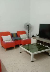 日得拉AZhomestay的客厅配有2把椅子和平面电视