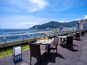 热海Pearl Star Hotel ATAMI的餐厅设有桌椅,阳台享有海景。