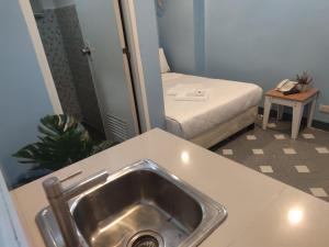 马尼拉Glory Hotel Cubao的一间带水槽的浴室和一张位于客房内的床