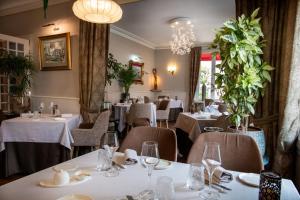 阿姆博斯洛奇酒店的一间设有白色桌椅的餐厅,种植了植物
