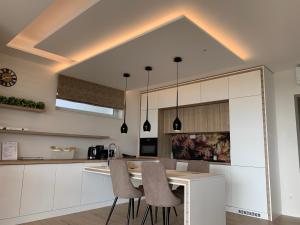 塞克萨德SXRD Luxus Apartmanok的厨房配有白色橱柜和桌椅