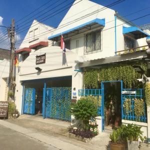 Ban Khlong ThewaBAAN CHANG Guesthouse的白色的建筑,街道上设有蓝色的门