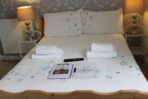 韦茅斯雷德克利夫酒店的一张带白色床单的床,配有书籍和毛巾