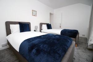 庞蒂浦Wern farm cottage的一间卧室配有两张带蓝色枕头的床