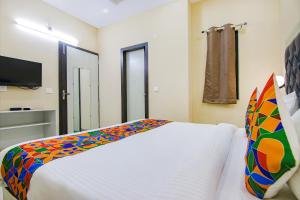 新德里FabHotel Ashok Vihar的卧室配有白色床和色彩缤纷的枕头