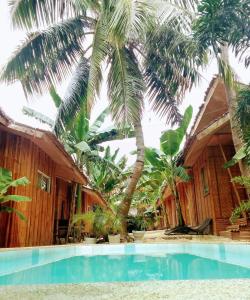 邦劳Ecostay Panglao Resort Hotel的棕榈树屋前的游泳池