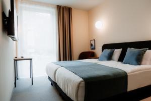 多特蒙德Moods Hotel Dortmund的一间卧室配有一张带蓝色枕头的床和一扇窗户。