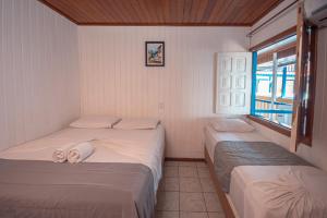 莫罗圣保罗Amendoeira Praia Hotel的带窗户的客房内设有两张单人床。