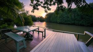 春蓬Rimsira的河边木甲板上的野餐桌和长凳