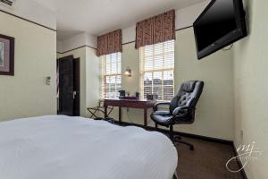 哈里森Hotel Seville的一间卧室配有一张床、一把椅子和一张书桌