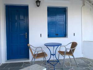 普拉提伊亚洛斯西弗诺斯Petradi Sifnos的两把椅子和一张桌子在两扇蓝色门前