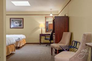 哈里森Hotel Seville的酒店客房配有一张床、一把椅子和一张书桌