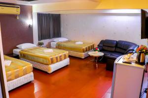 曼谷Visiting Card Hotel & Resort的酒店客房,设有三张床和一张沙发