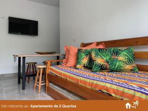 乌巴图巴BEIRA MAR - PRAIA Do LÁZARO的一间卧室配有一张带桌子的床和一台电视。