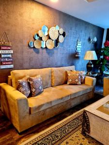 伊斯兰堡Royal Residencia Centaurus的客厅里一张棕色的沙发,墙上挂着盘子