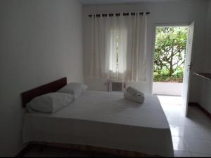特林达德Casa Brasil pousada e lazer的白色卧室设有一张大床和窗户