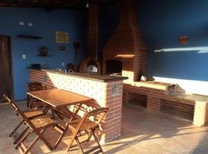特林达德Casa Brasil pousada e lazer的庭院配有桌椅和砖炉