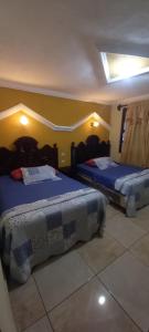 圣佩德罗拉拉古纳Hotel Tinamit的一间卧室配有两张带蓝色棉被的床