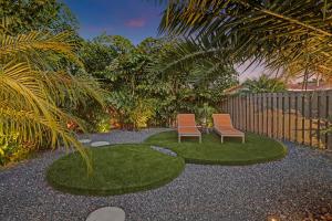 劳德代尔堡Stylish Luxury Tropical Junior Suite的两把椅子在院子里,有草地和栅栏