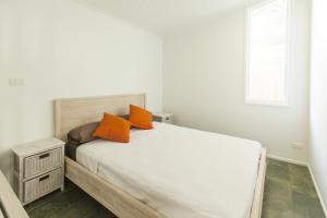 Holloways Beach漂流海滩逍遥度假屋的一间卧室配有带橙色枕头的床