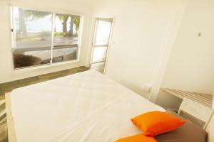 Holloways Beach漂流海滩逍遥度假屋的窗户客房内的一张带橙色枕头的床