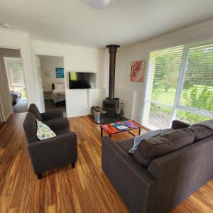 托基Bells Beach Cottages - Pet friendly cottage with wood heater的客厅设有两张沙发和一个壁炉