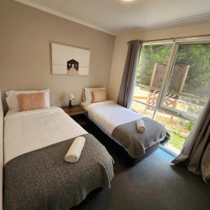 托基Bells Beach Cottages - Pet friendly cottage with wood heater的带窗户的客房内的两张床